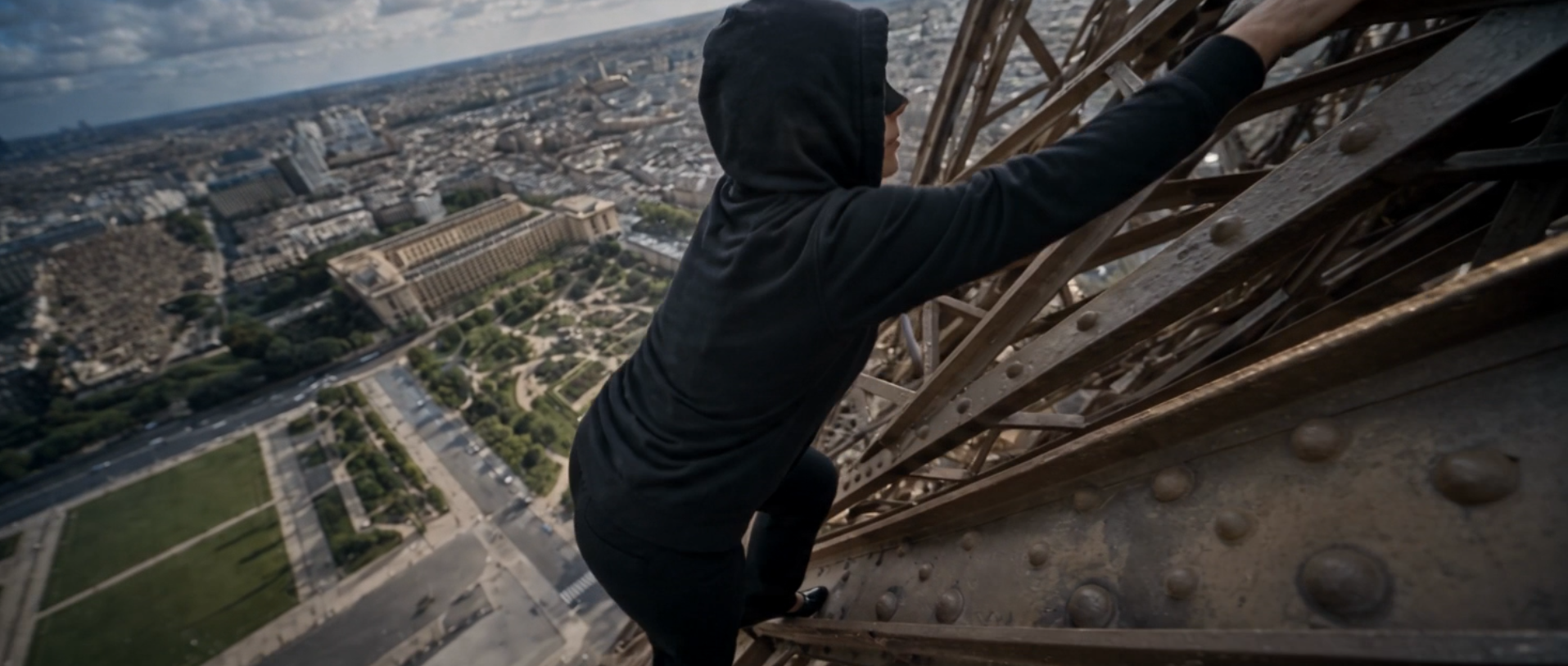 Myriam escaladant la structure métallique de la Tour Eiffel au-dessus du Trocadéro