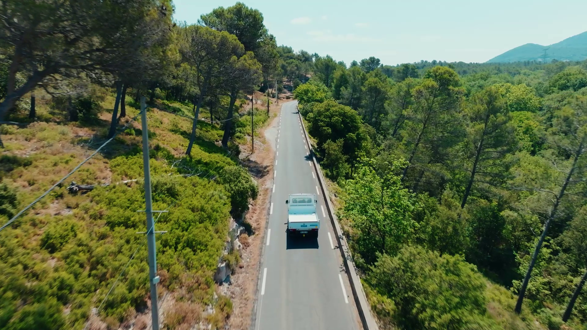 Vue aérienne d'un véhicule roulant sur une route forestière, filmée par drone — ORYGEN FILMS